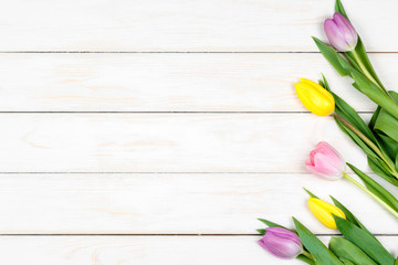 Bunch of colored tulips lying on a white wooden background