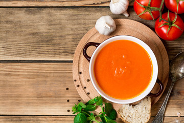 Tomato soup in ceramic bowl on wooden background.
