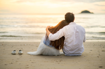 Fototapeta na wymiar Couple watching sunset in the beach romantic scene