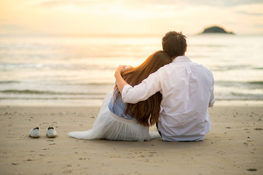Couple watching sunset in the beach romantic scene