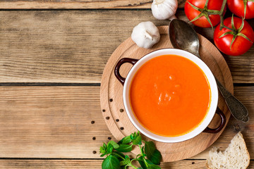 Tomato soup in ceramic bowl on wooden background.