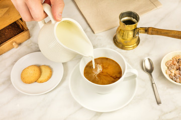 Milk poured into cup of coffee