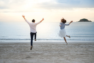 Couple enjoy the beach with cheerful jump