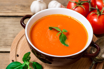 Tomato soup in ceramic bowl on wooden background.