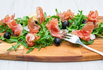 chopping board with aragula and raw ham