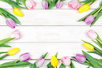 Pink and yellow tulips on a white wooden background