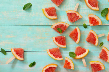 Slices of red grapefruit popsicle on a vintage wooden background, copy space. The concept of a healthy diet and detox diet.