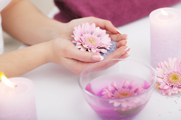 Obraz na płótnie Canvas Spa Procedure. Woman In Beauty Salon Holding Fingers In Aroma Bath For Hands. Closeup Of Female Nails Soaking In Bowl Of Water With Pink Flower Petals. Aromatherapy. High Resolution