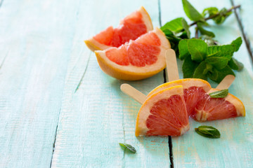Slices of red grapefruit popsicle on a vintage wooden background, copy space. The concept of a healthy diet and detox diet.