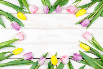 Pink and yellow tulips lying on a white wooden background