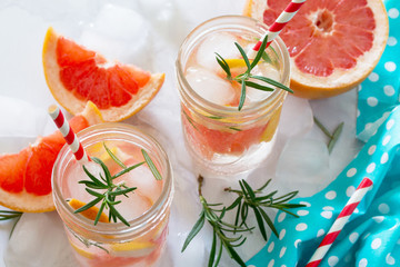 Refreshing summer drink with grapefruit and rosemary on a stone background. The concept of eating vegetarians, fresh vitamins, a homemade refreshing fruit drink.