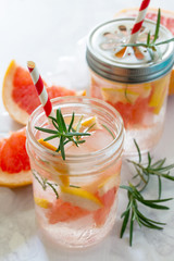 Refreshing summer drink with grapefruit and rosemary on a stone background. The concept of eating vegetarians, fresh vitamins, a homemade refreshing fruit drink.