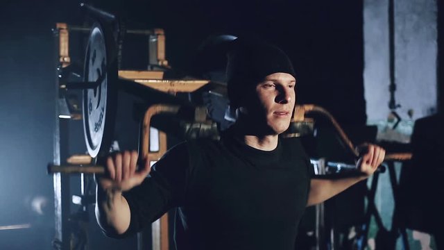 A man pumps the muscles on the simulator in the gym close-up