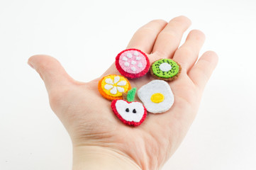 Handmade toy in the form of fruits and food made of felt stretched on a palm. Close-up of crafts with embroidery in hand