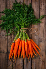 Bunch of fresh carrots with green leaves over wooden background. Vegetable.Food or Healthy diet concept.Vegetarian.Copy space for Text. selective focus.