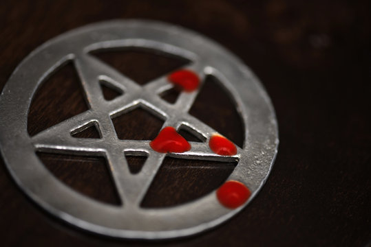 old pentagram with drops of blood lies on a wooden background. black mass. black magic ritual