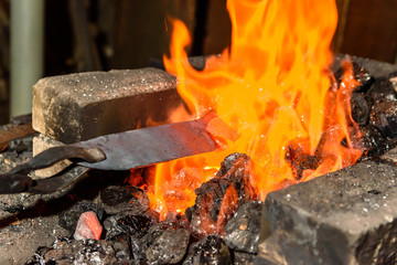 Warming up the metal in heat. The forge.