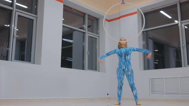 Plastic beautiful girl gymnast on acrobatic circus ring in blue suit. Aerial ring. Acrobatic and sport concept