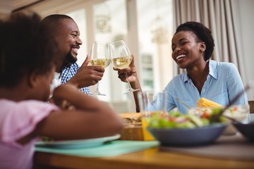 Family toasting glasses of wine while having meal 