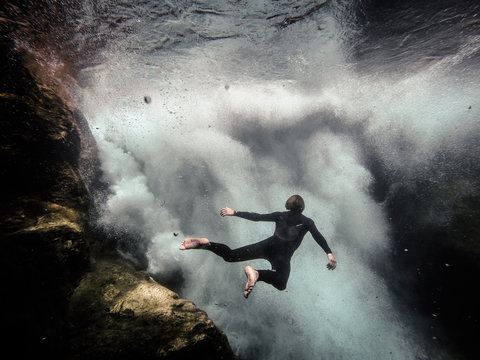 man floating in front of underwater waterfall