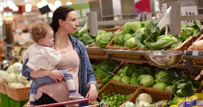 Mother and daughter buying vegetables in grocery store
