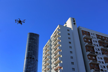 Dron latający na tle wieżowca Sky Tower i apartamentowca we Wrocławiu.