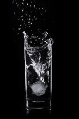 A glass of water and ice cube on a black background