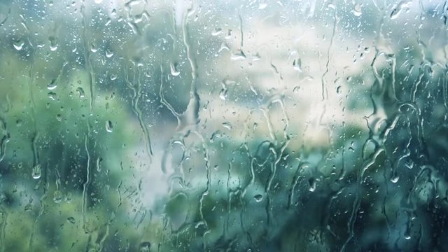 Heavy windy thunderstorm and close-up of water droplets on glass window. Selective focus used.