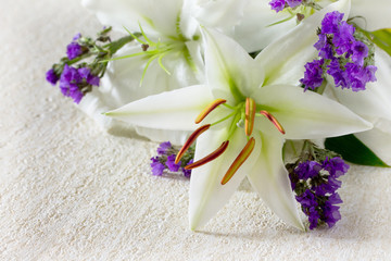 Obraz na płótnie Canvas Wedding or birthday background. Beautiful fresh white lily flowers on a stone background. Copy space.