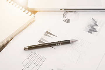 pen with graph financial documents on table in office.