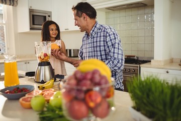 Father and daughter preparing smoothie in kitchen