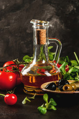 Ingredients of Italian cuisine. Selection of products for salad. Olive oil, lettuce leaves, tomatoes. On a black dark shale concrete stone kitchen table. copy space