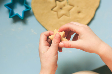 A child making cut-out cookies with cookie cutters on a blue table