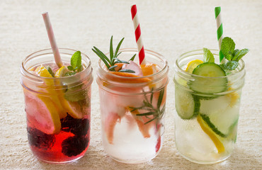 Fruit refreshing water. Various summer drinks with blackberries, grapefruit, lemon and mint on a stone background. The concept of healthy and dietary nutrition.