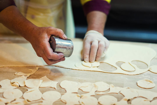 round shape of the dough and rolling pin with flour on the table,Roll out the dough for damplings,Preparing, cooking, making homemade ravioli, pelmeni or dumplings with meat on wooden table