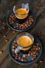 Two cups of espresso and coffee beans on a wooden table