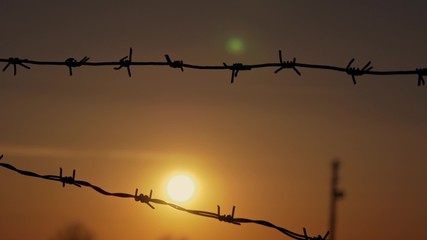 Fototapeta na wymiar barbed wire prison sunset orange background