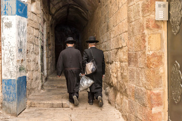 A narrow street in East Jerusalem with a couple of religious Jews.