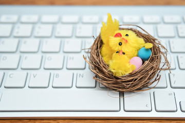 Toy - basket with chickens and easter eggs lies on a white computer keyboard