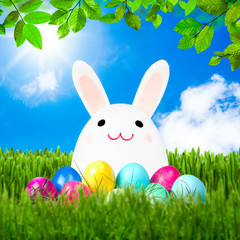 Lustiger Osterhase sitzt auf einer Wiese mit Ostereiern