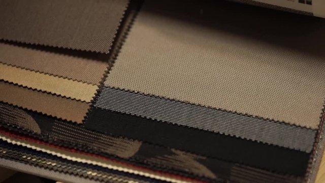 Female hands flips a fabric sample for curtains, upholstery upholstery, panels and car interior

