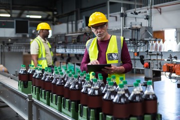 Factory worker with digital tablet monitoring drinks 