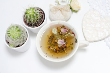 Green yellow white natural herbal tea harvested on plantations of bio eco healthy brewed in a cup. Mint lime-tree linden berries whole buds of roses petals welded in cup home love surprise background.