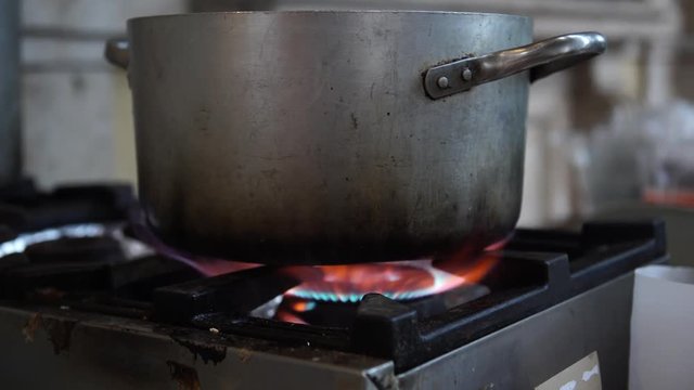 An old dirty cooker with a gas on and a old pan on it, selective focus, 4K