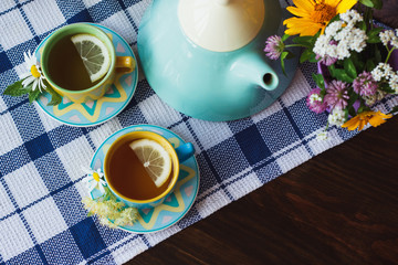 Cups of herbal tea with chamomile and mint leaves on the wooden background