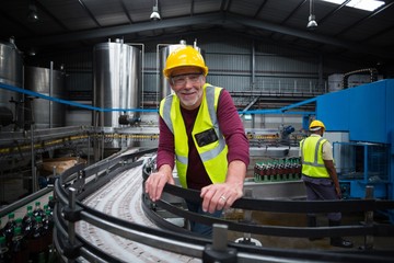 Smiling factory worker leaning on production line