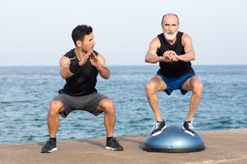 Senior macht Training mit Balanceplattform am Meer