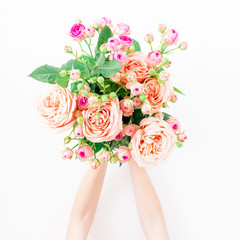 Bouquet with pink roses in woman hands on white background. Flat lay, top view. Floral background