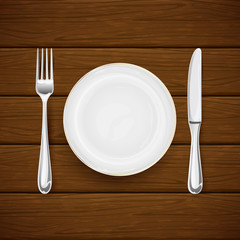 Plate with fork and knife on brown wooden background