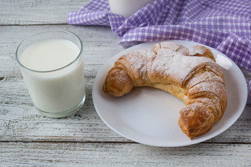 Croissant with milk on old wooden table for breakfast background.